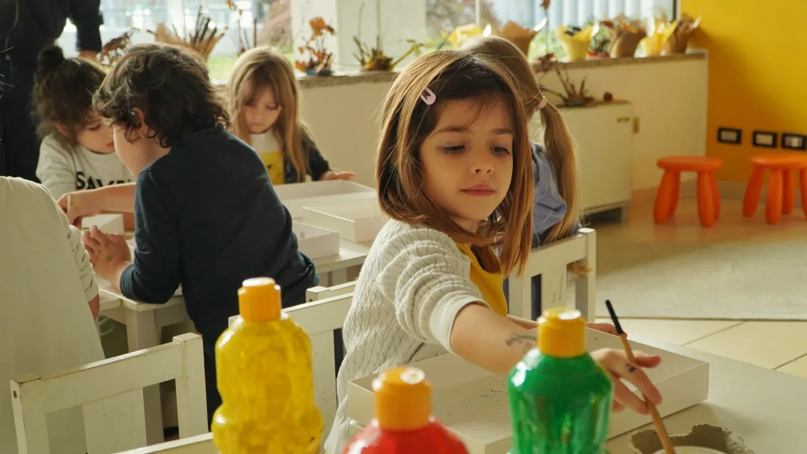 Una bambina sperimenta con colori e materiali in aula
